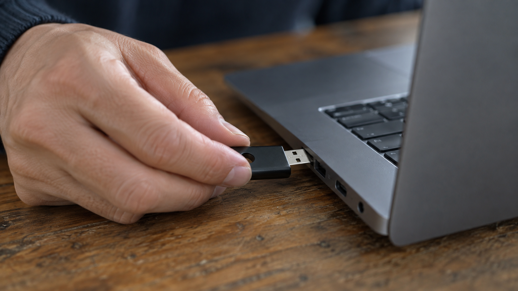 Hand placing a USB security key into a laptop.
